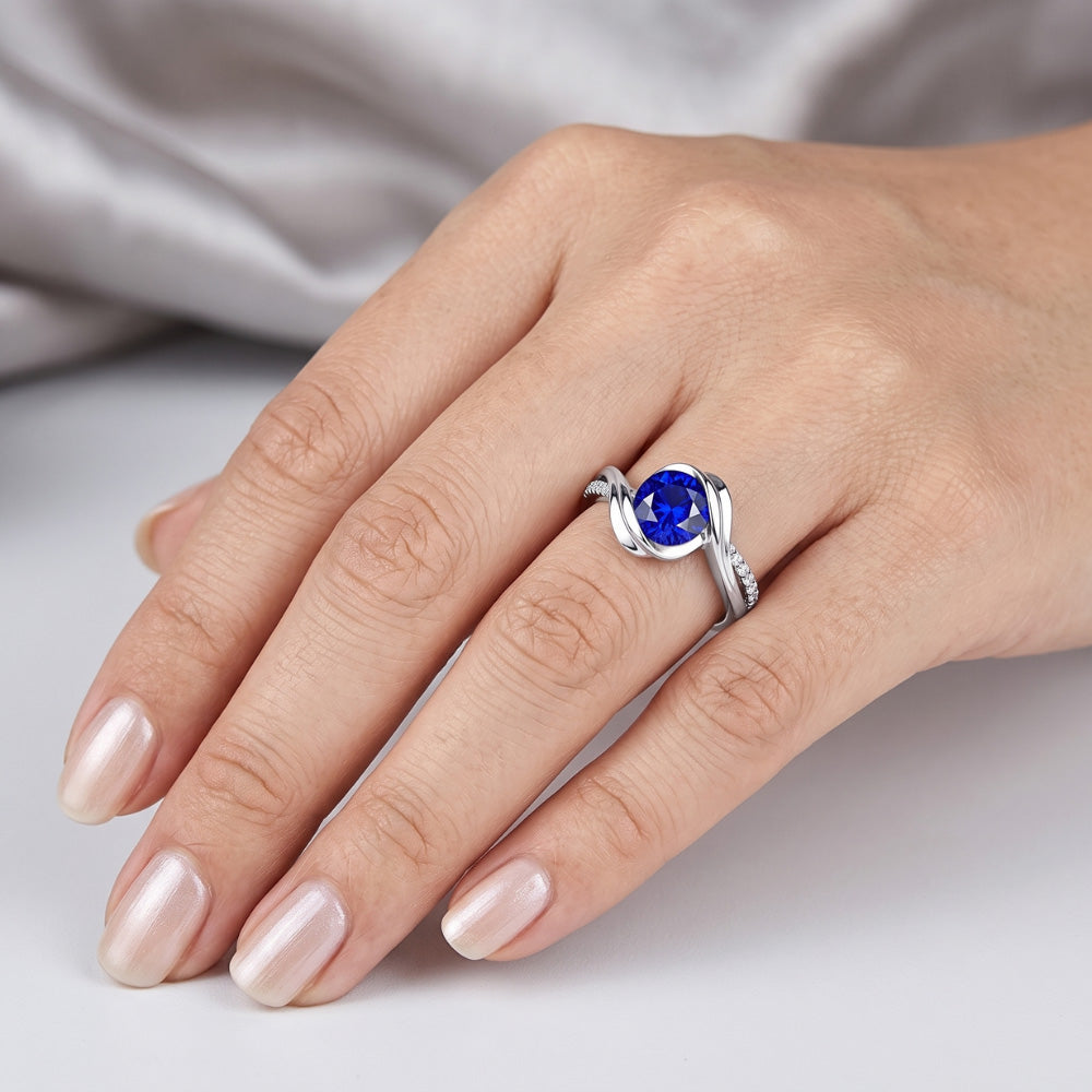 Anello in oro bianco 14K e diamanti con zaffiro tondo. 1,50 carati. stelo intrecciato